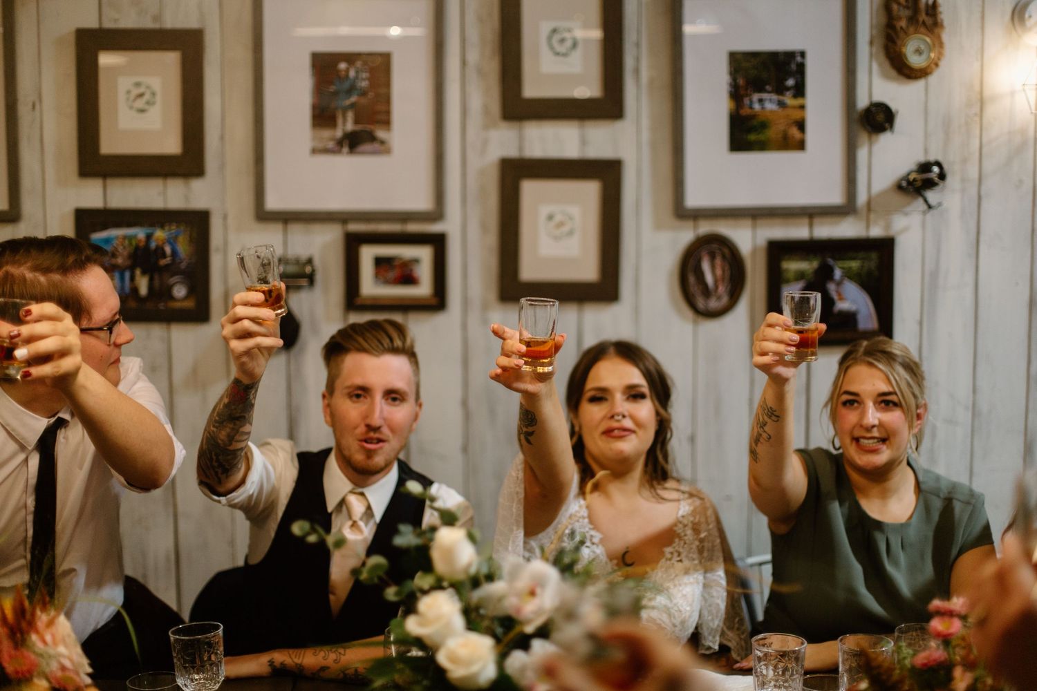 Wedding reception guests raising glasses in a toast during celebration.