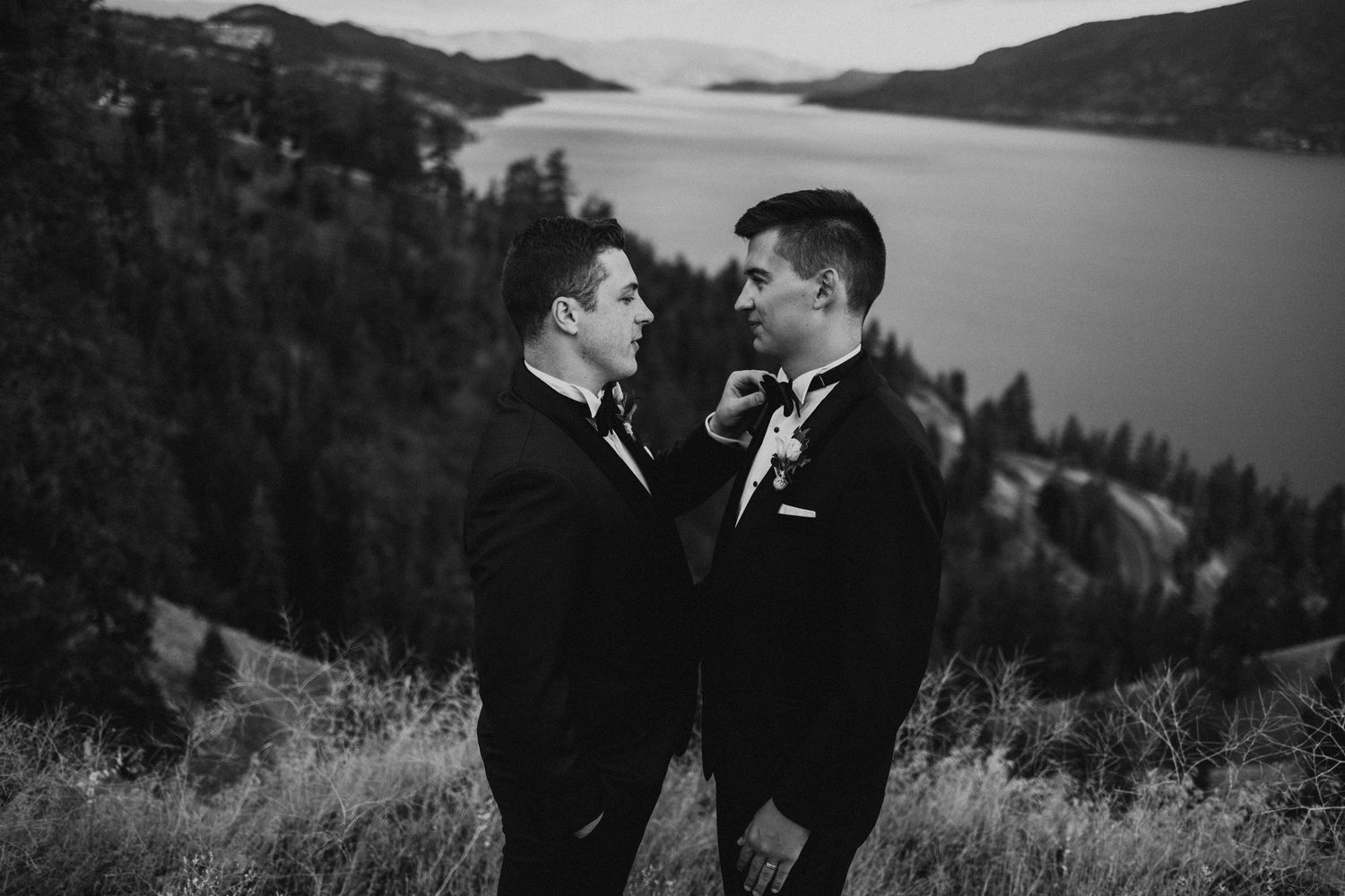 A romantic moment captured in black and white with a scenic lake and mountain backdrop.