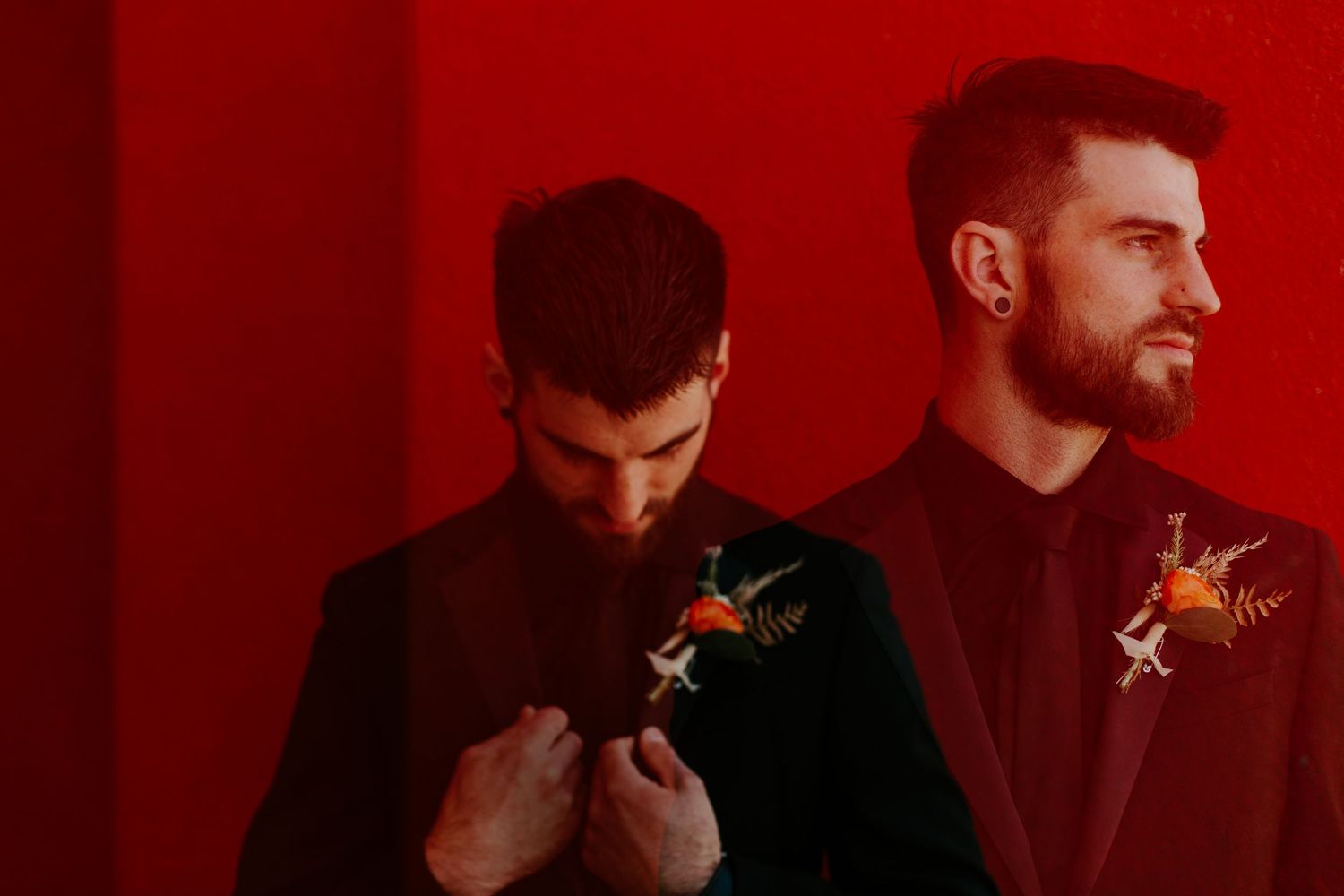 Artistic portrait of two people in black suits against red background.