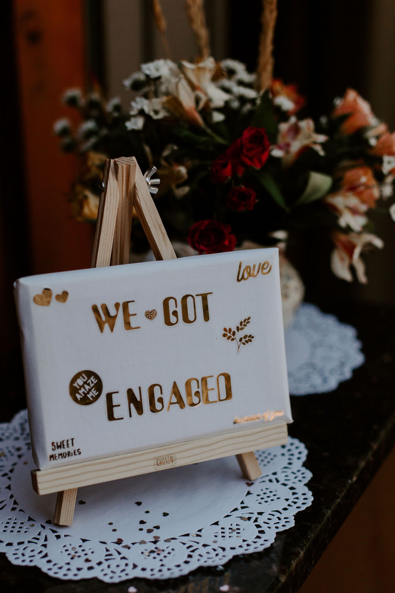 Mini wooden easel displaying 'We Got Engaged' sign with floral arrangement.