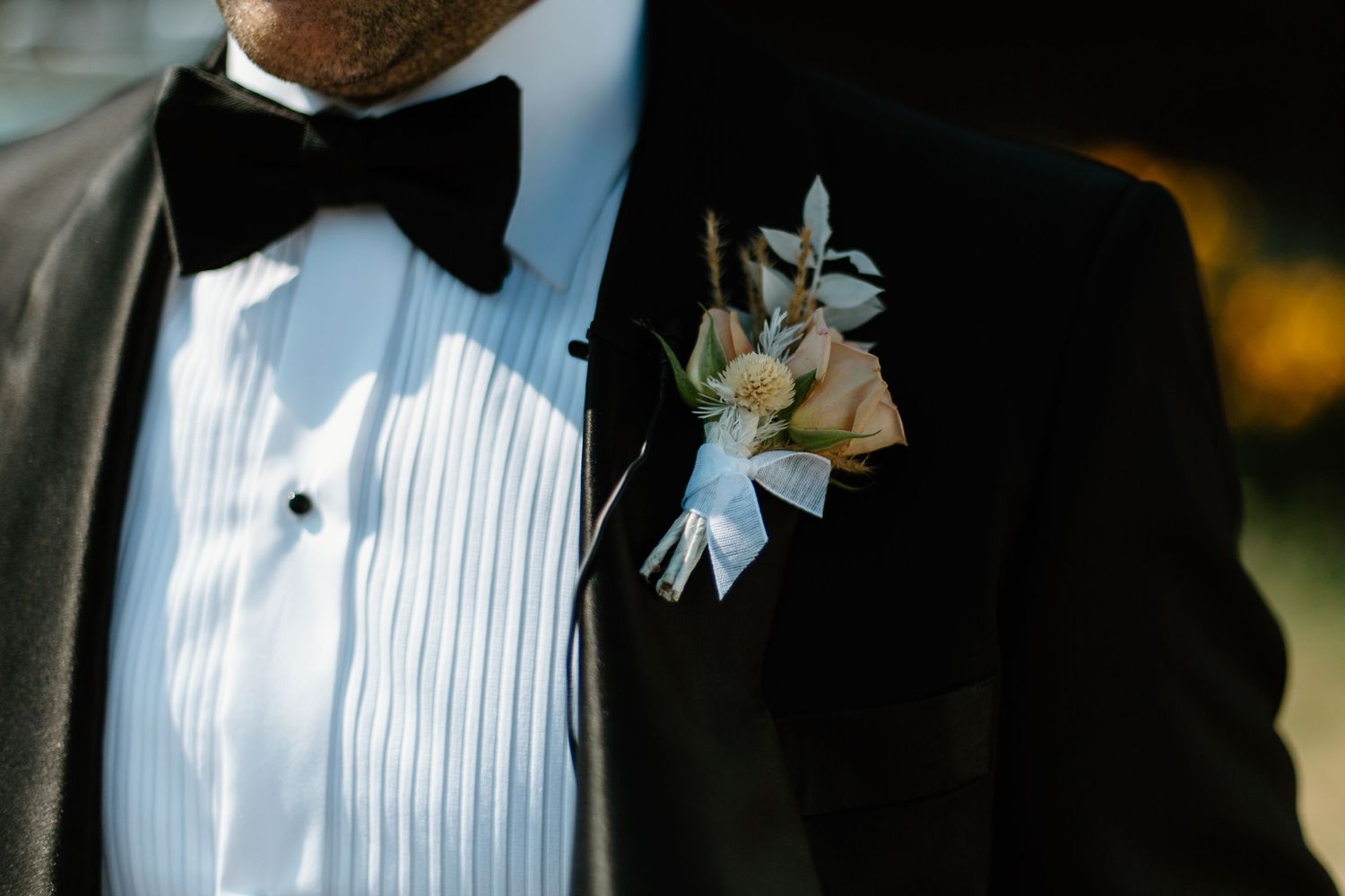 Close-up detail of formal black tuxedo with white boutonniere.