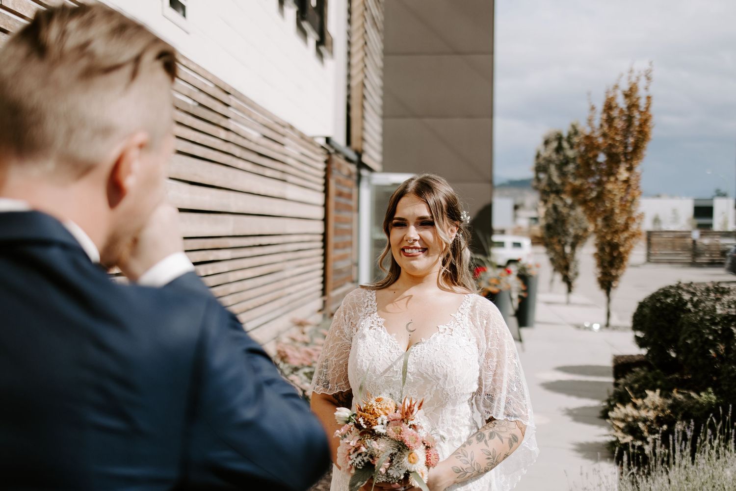 Wedding couple sharing a moment outside urban building with fall foliage.