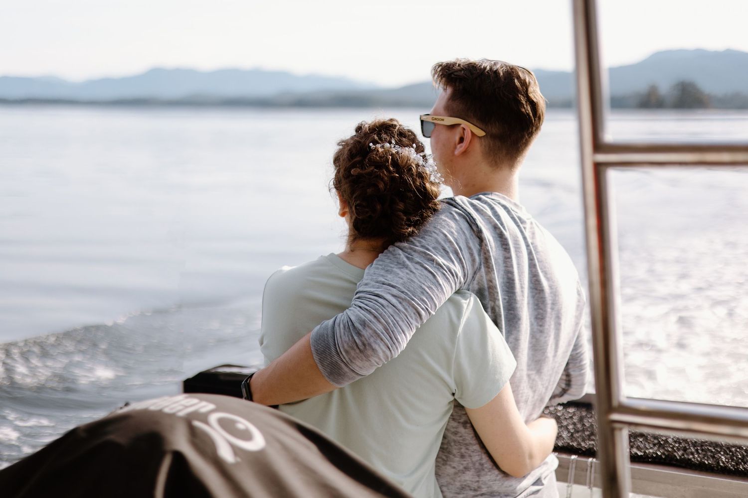 A couple sits together on a boat deck overlooking scenic mountain views across the water.