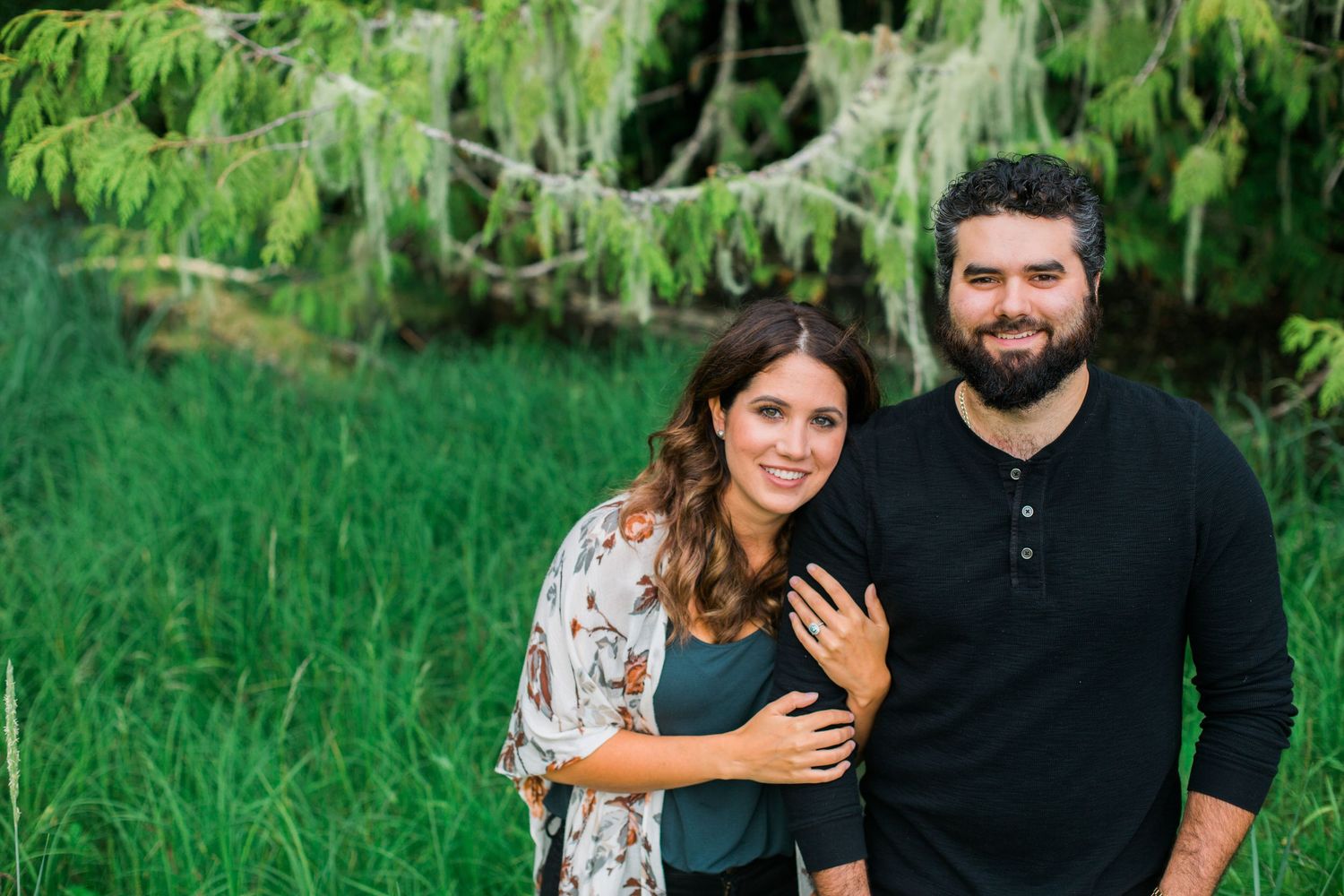 A couple enjoying a romantic moment together in a lush green forest setting.