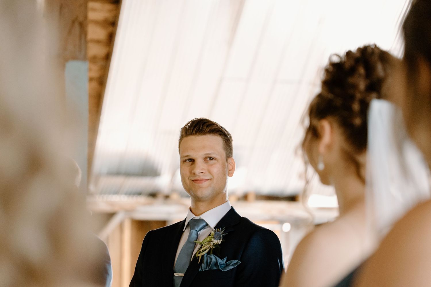Intimate wedding ceremony moment captured in rustic barn setting with draped white fabric decor.