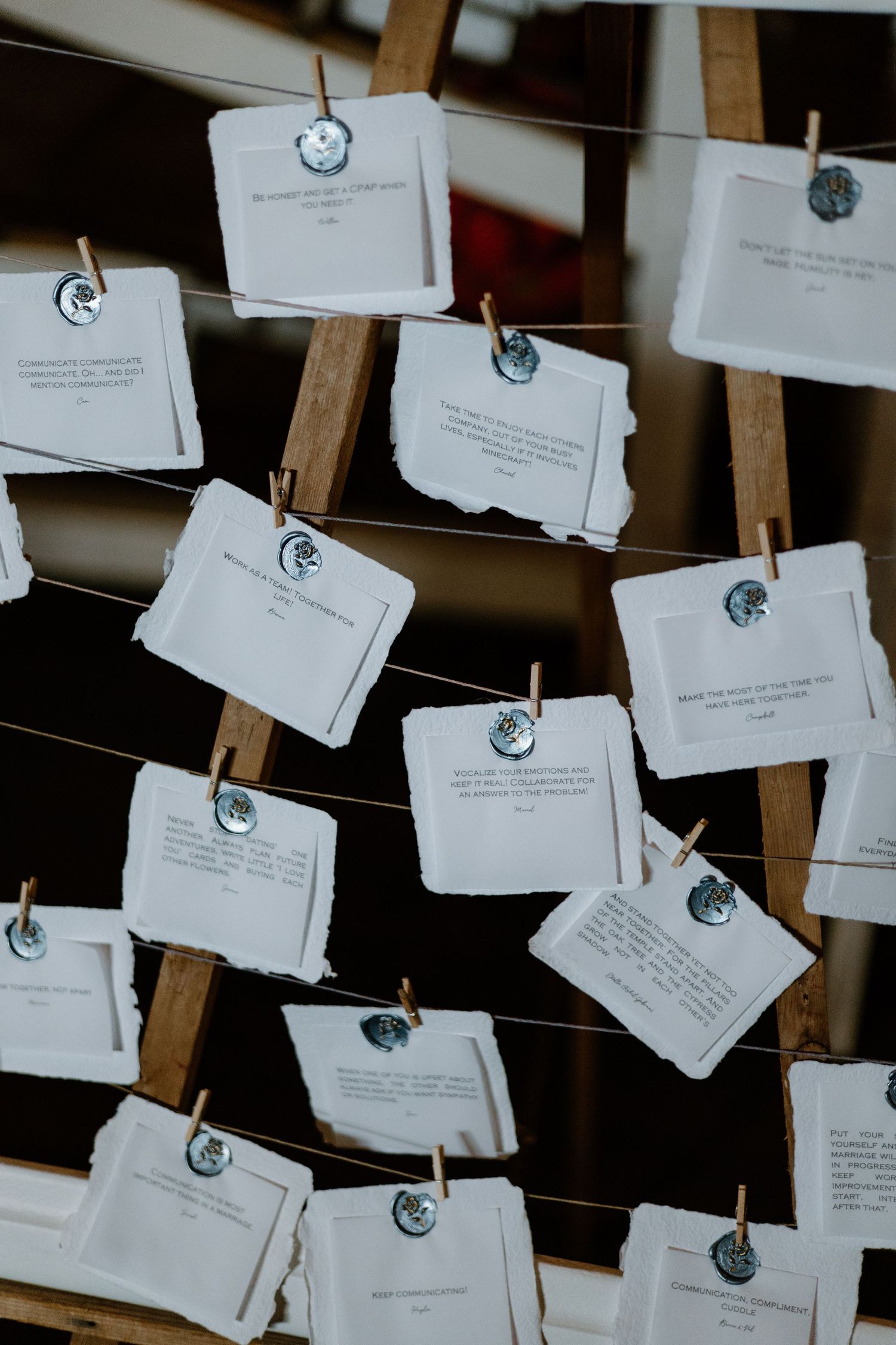 Wedding seating cards displayed on strings against a rustic wooden background.