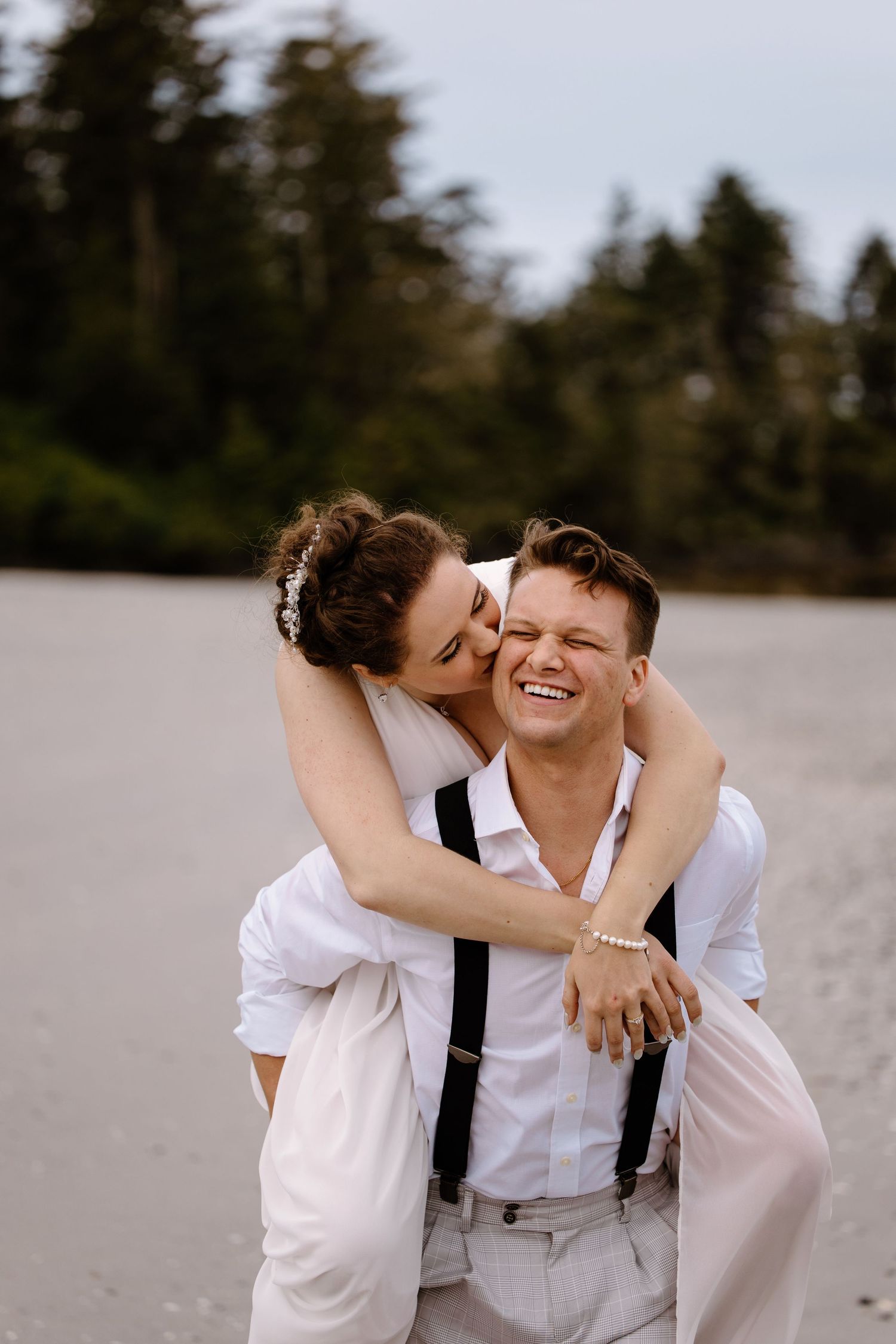 Romantic moment between newlyweds sharing laughter on a beach.