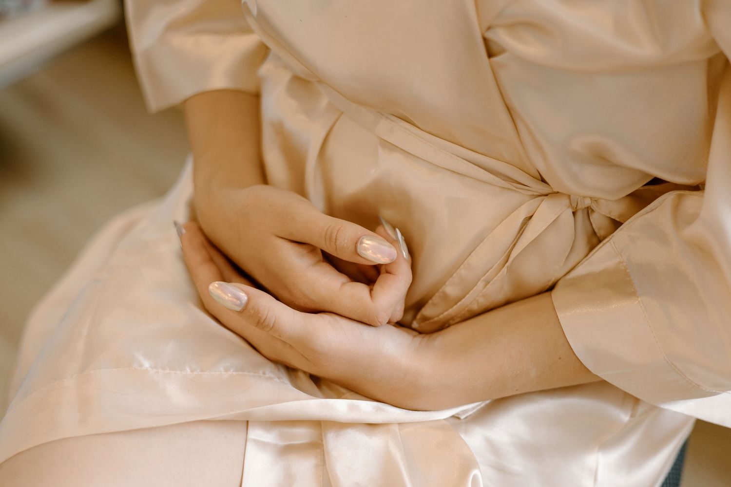 Close-up detail of cream colored satin fabric with gentle folds.