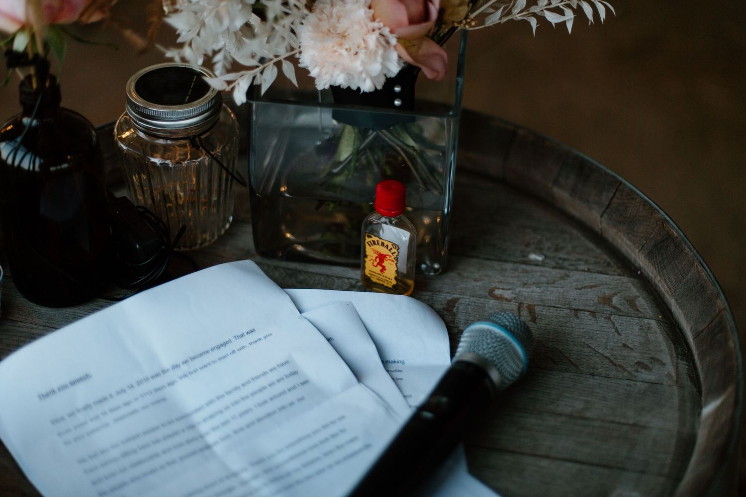 Wedding details including handwritten notes and delicate floral arrangements on a dark wooden surface.