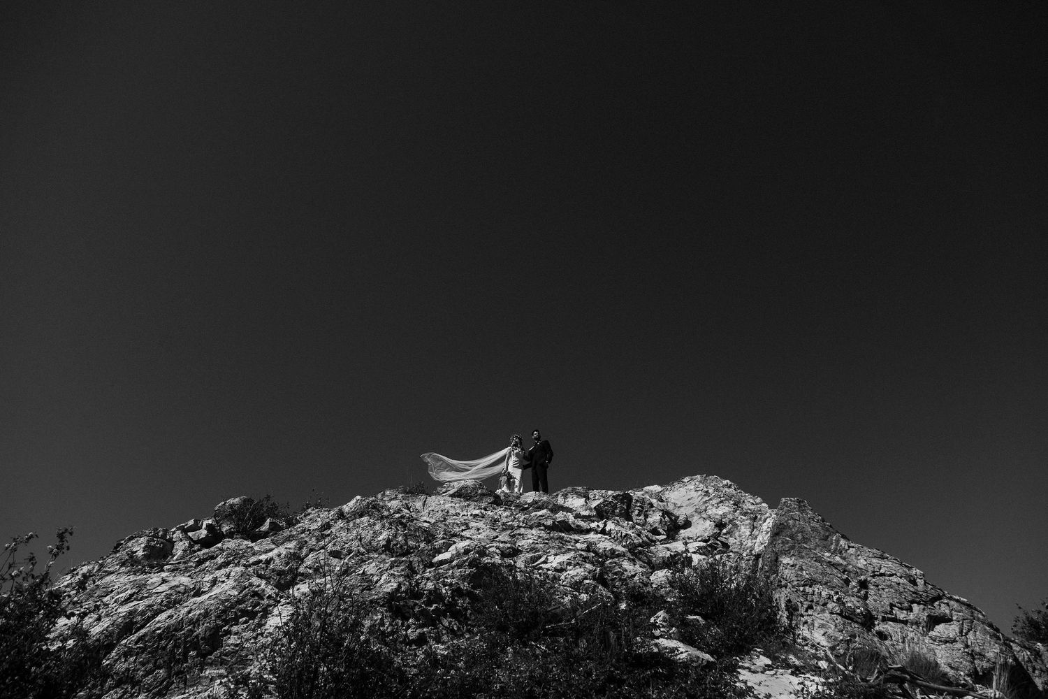 Dramatic black and white mountainous landscape with rocky terrain and dark clouds.
