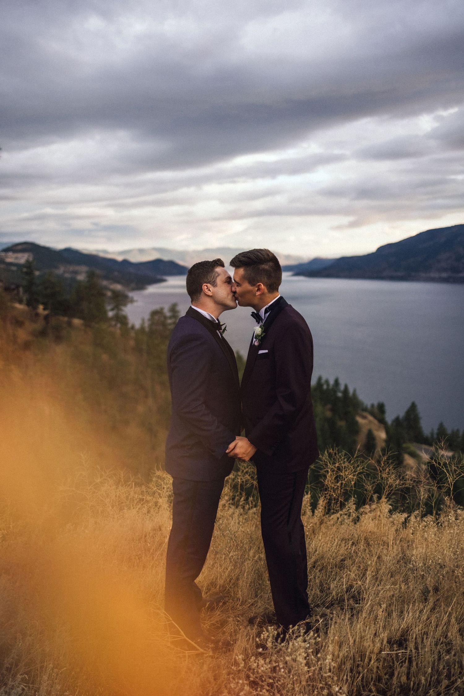 Intimate moment between couple against scenic mountain landscape and moody sky.