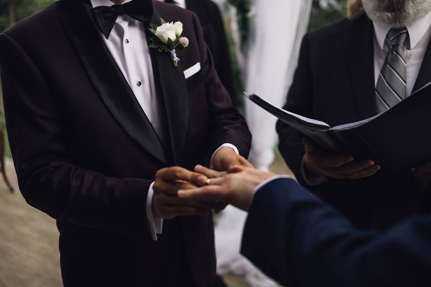 A close-up of hands exchanging rings during a wedding ceremony.