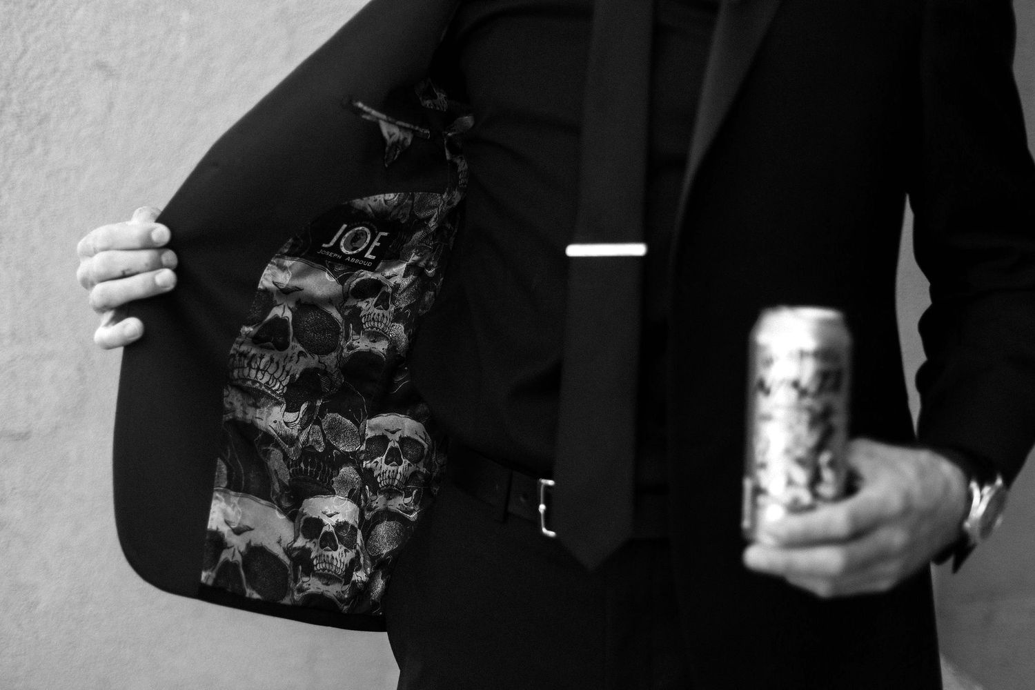 Detail shot of a suit jacket with skull pattern lining and a drink can.