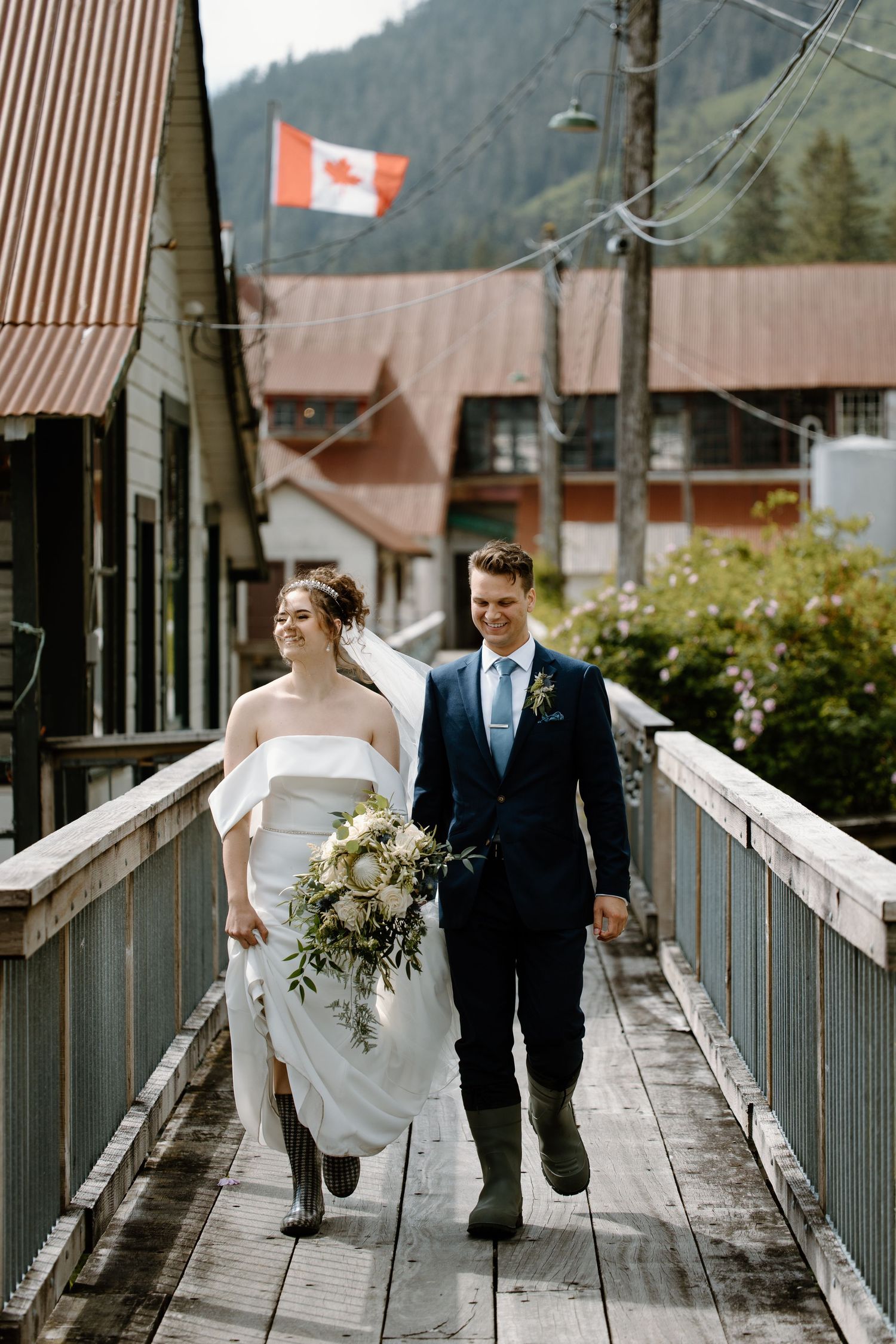 Wedding couple walking and laughing together on an elevated wooden boardwalk in a mountain town.