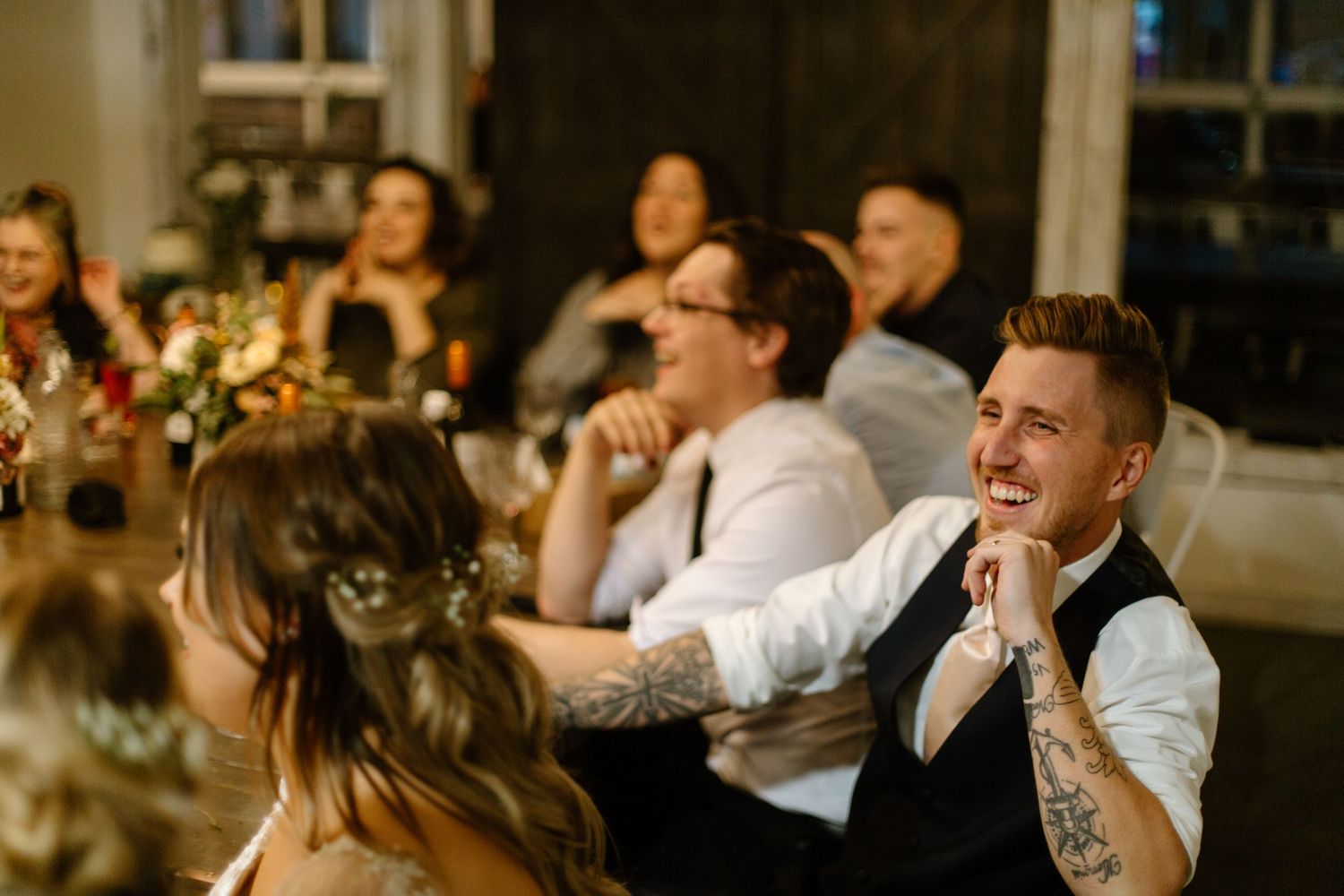 Reception guests enjoying a celebration at a dimly lit wedding venue.