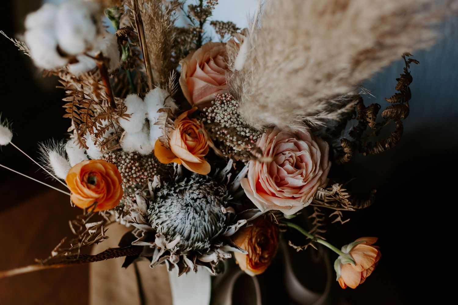 A collection of romantic floral arrangements with peach roses and delicate greenery in warm, moody lighting.