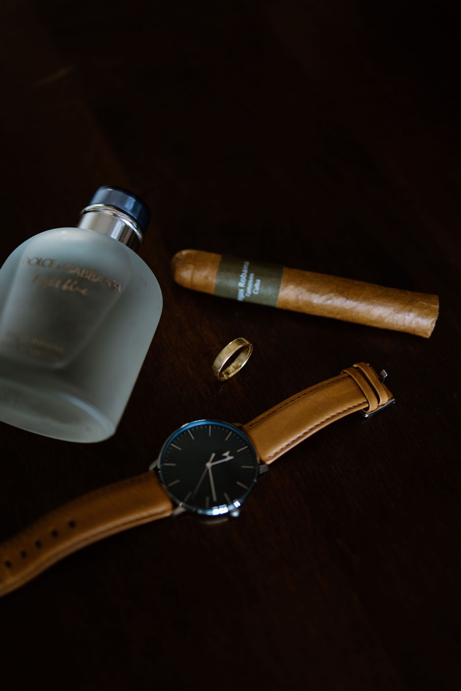 Artful closeup of a cigar and frosted glass against dark background.