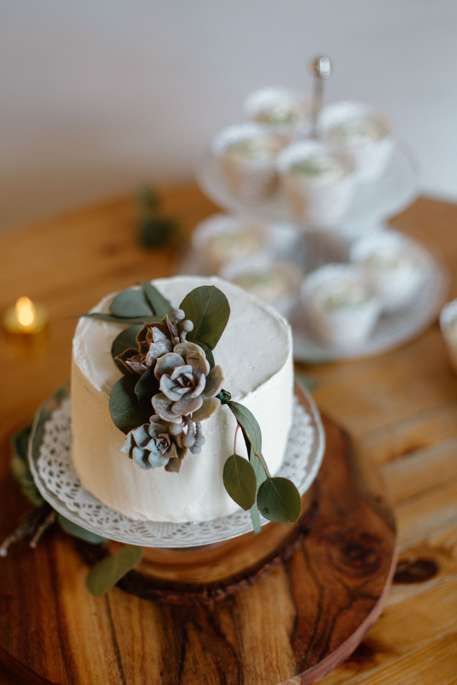 Small white wedding cake decorated with delicate floral accents and green foliage.
