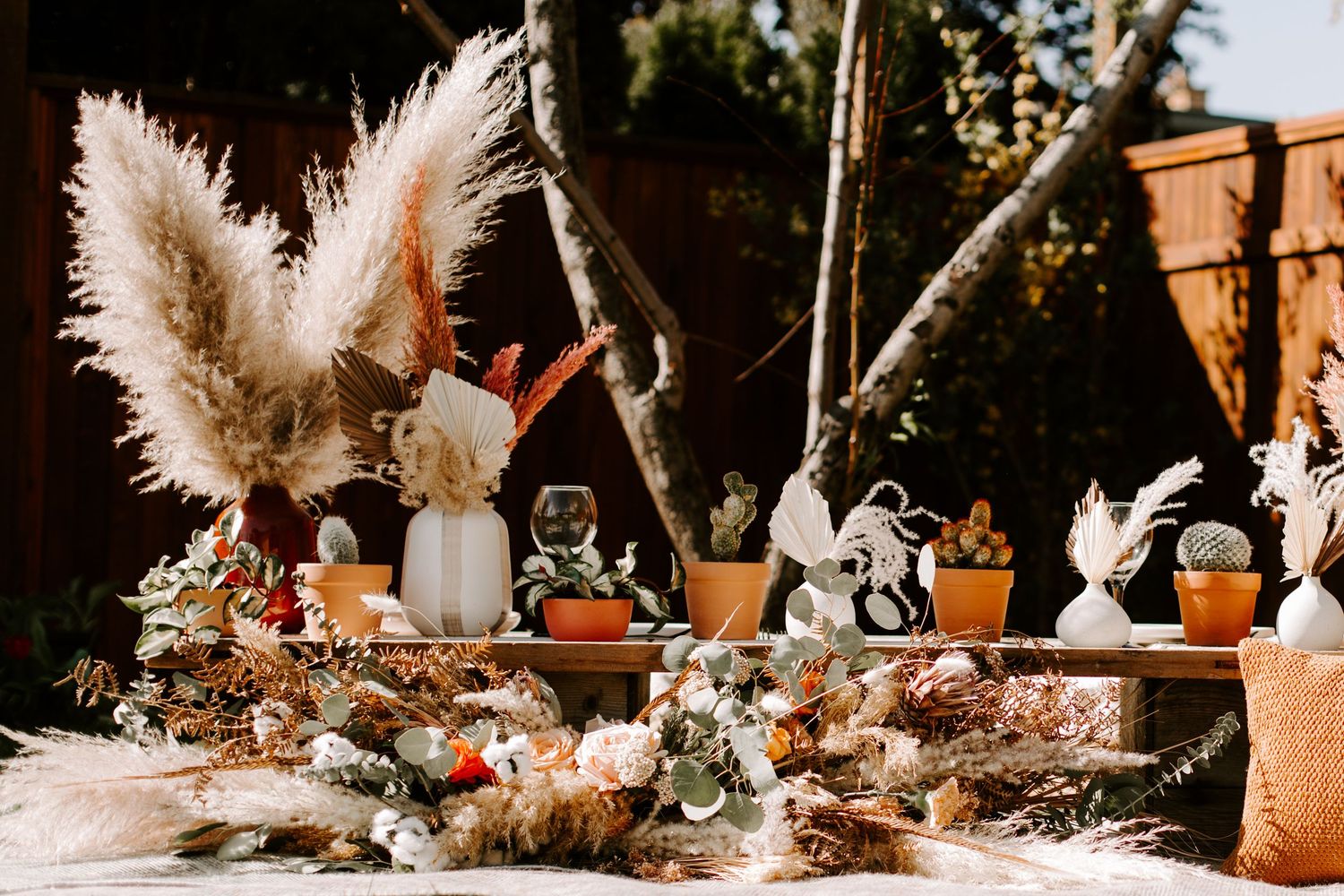 Bohemian wedding decor featuring pampas grass and small decorative figurines.