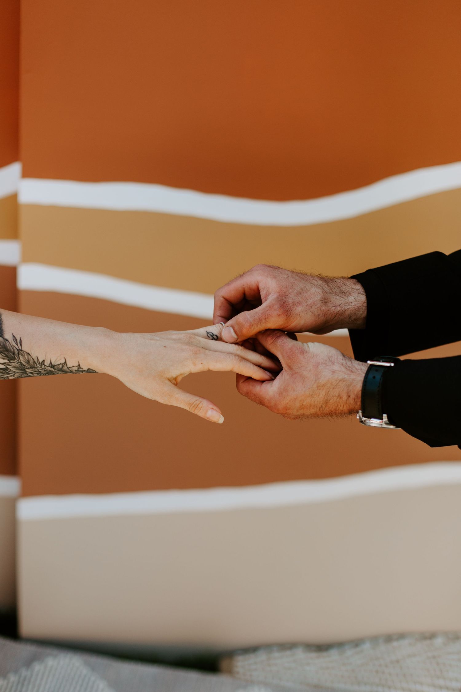 Two hands reaching towards each other against a warm brown background in a minimalist composition.