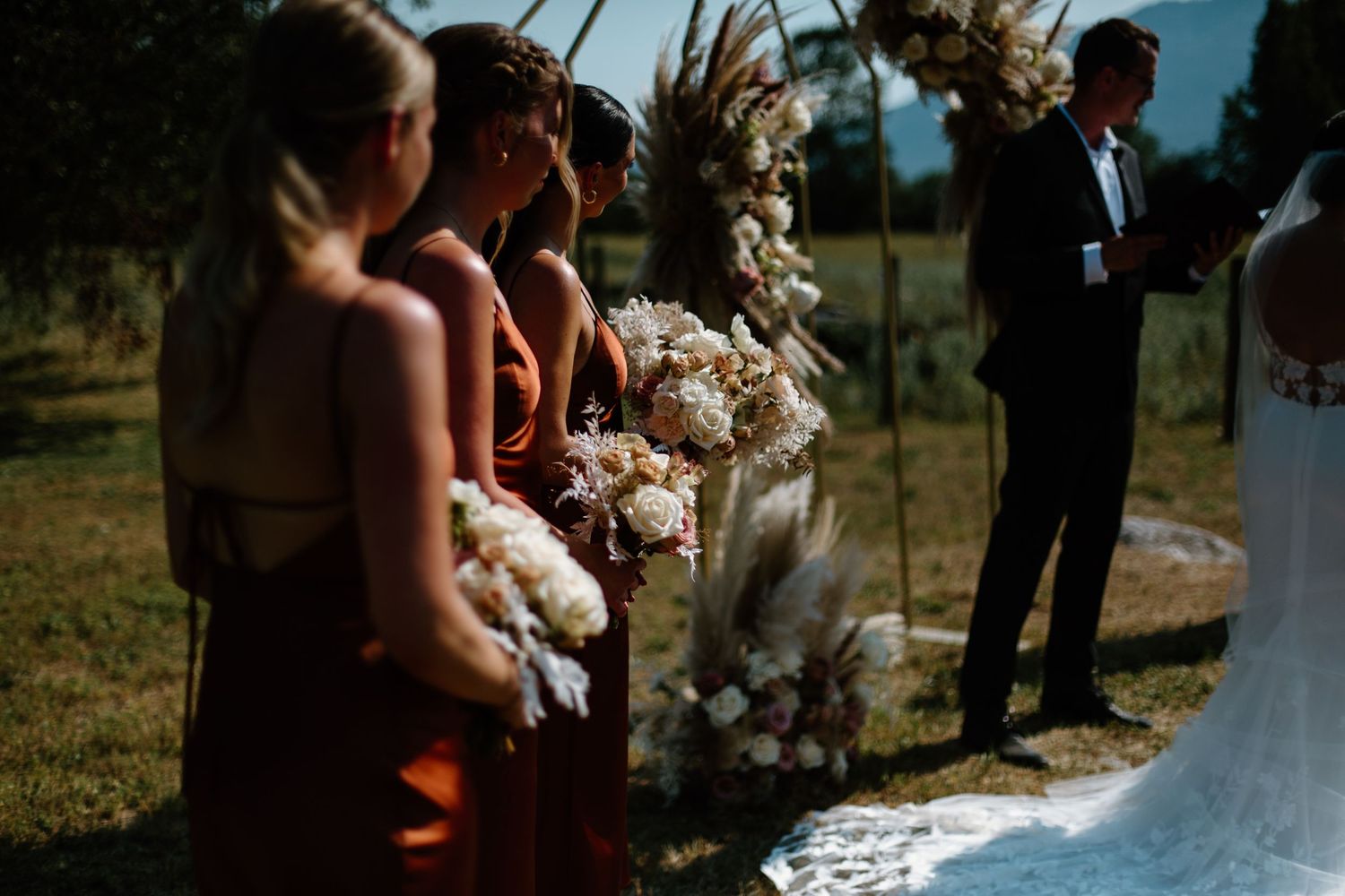 Outdoor wedding ceremony captured in warm sunlight with floral decorations.