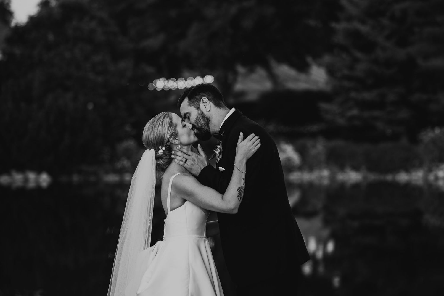 A tender black and white moment between newlyweds sharing an intimate kiss.
