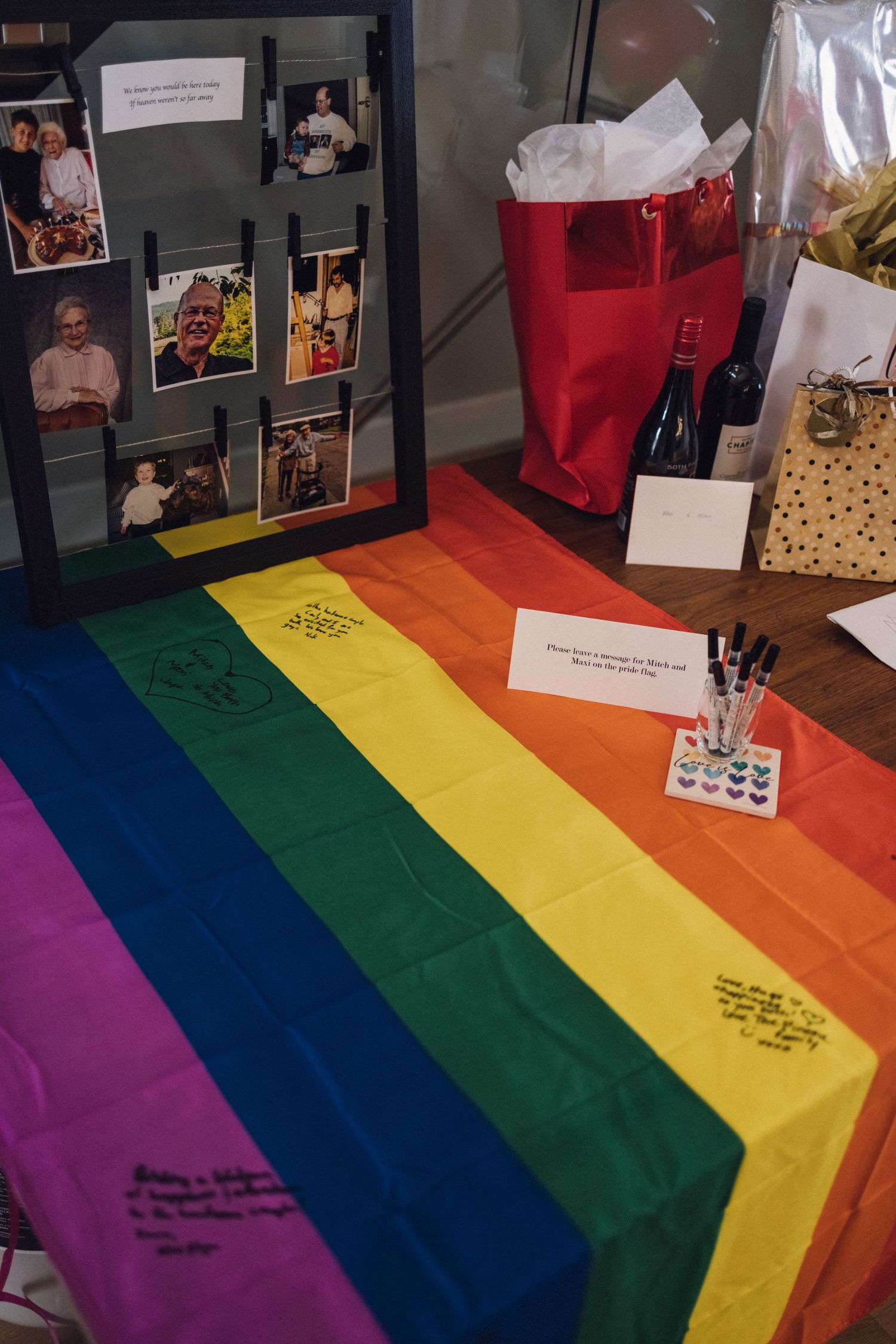 A pride flag table runner with rainbow stripes decorates a display featuring photos and memorabilia.