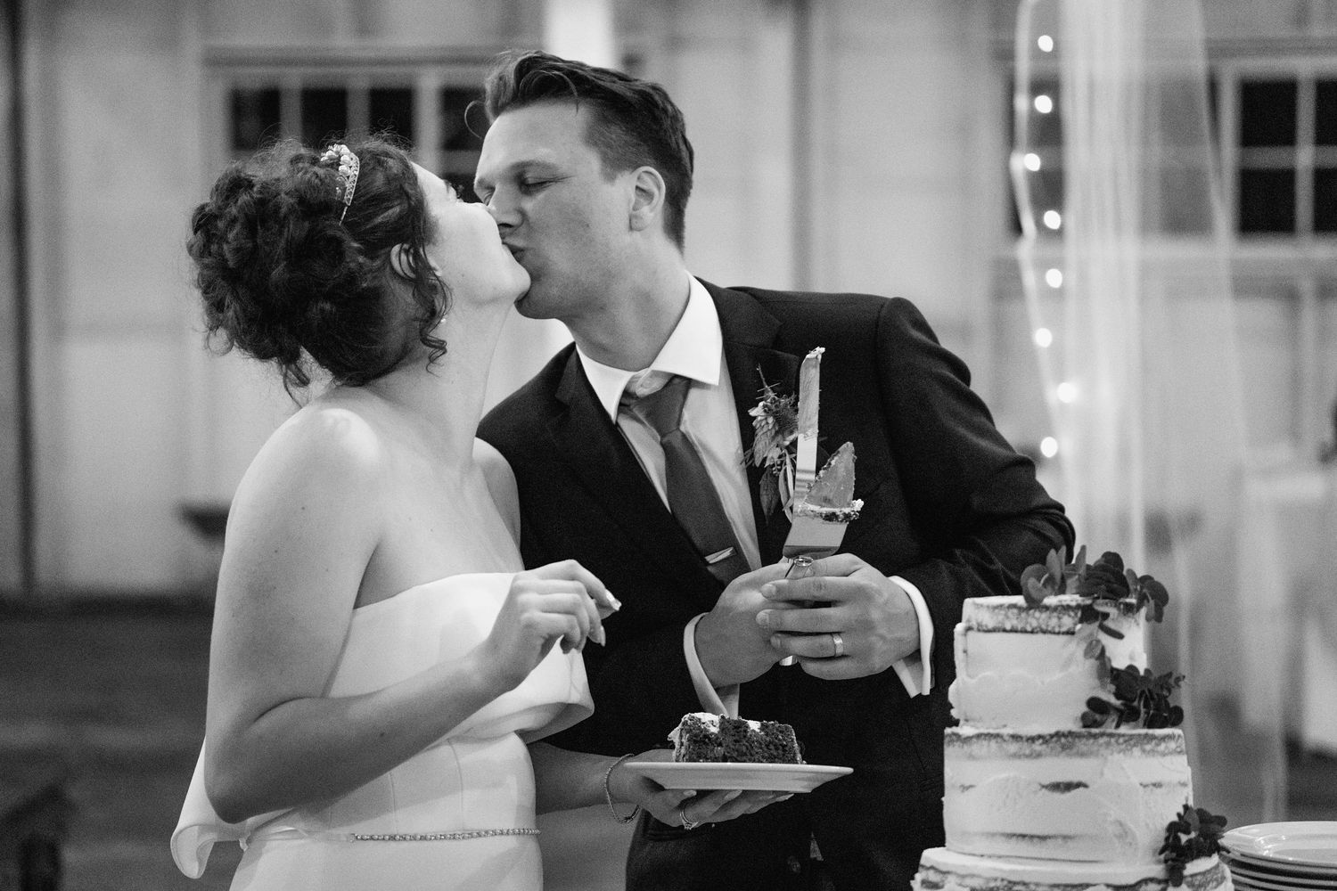 Black and white photo of newlyweds sharing cake at their wedding reception.