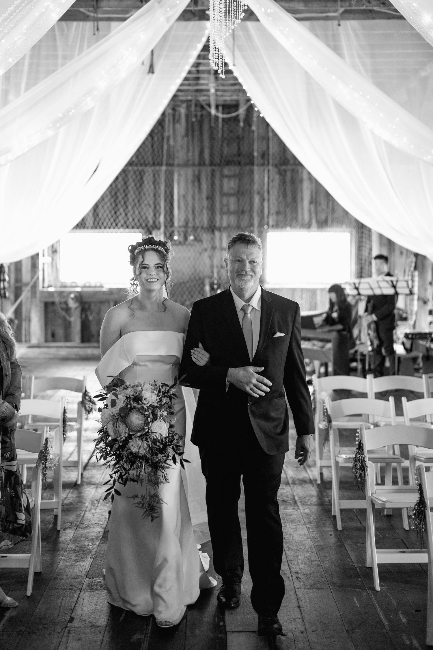 Black and white photo of wedding ceremony in rustic barn setting.