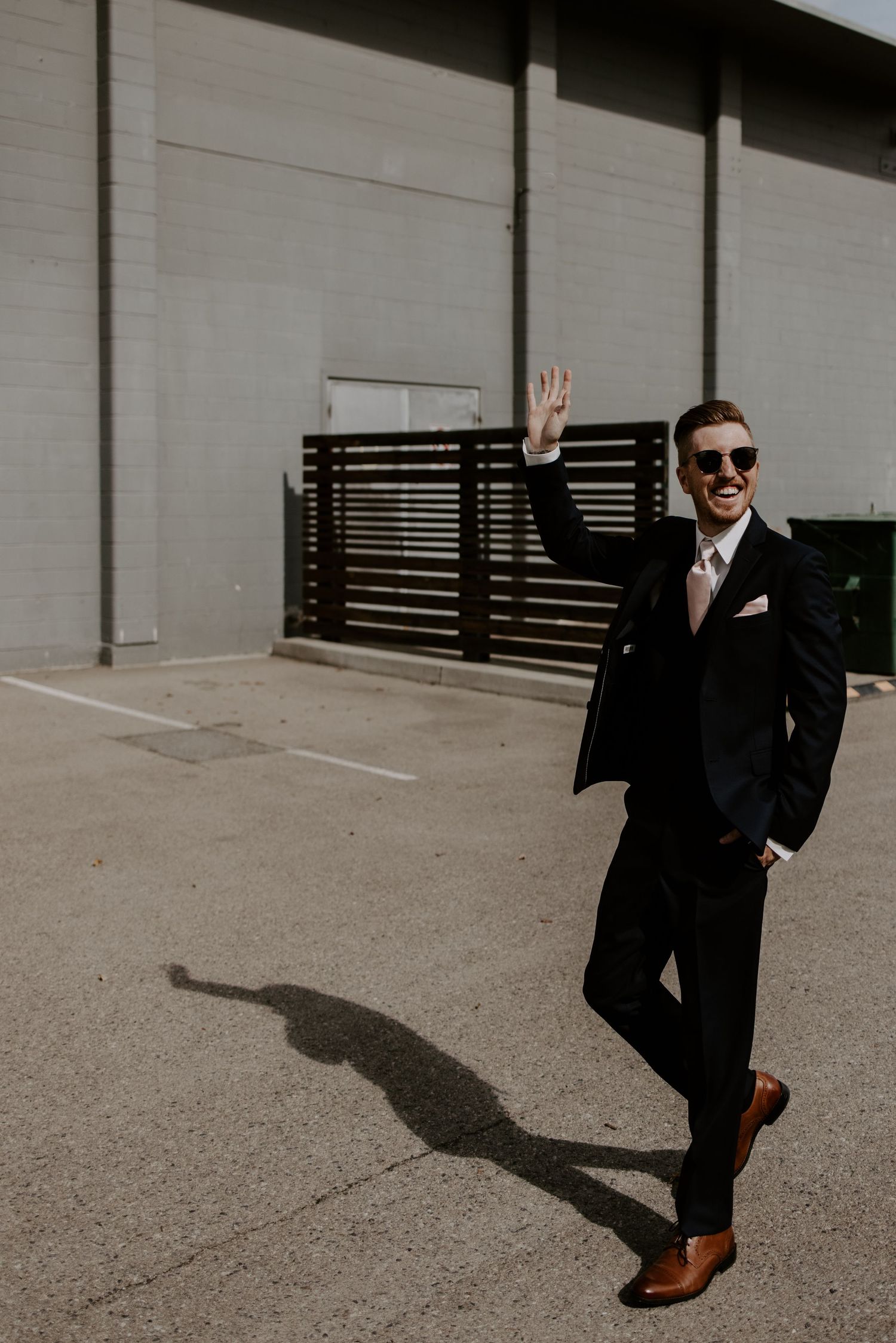 Figure in a black suit and sunglasses casting a dramatic shadow in an urban setting.