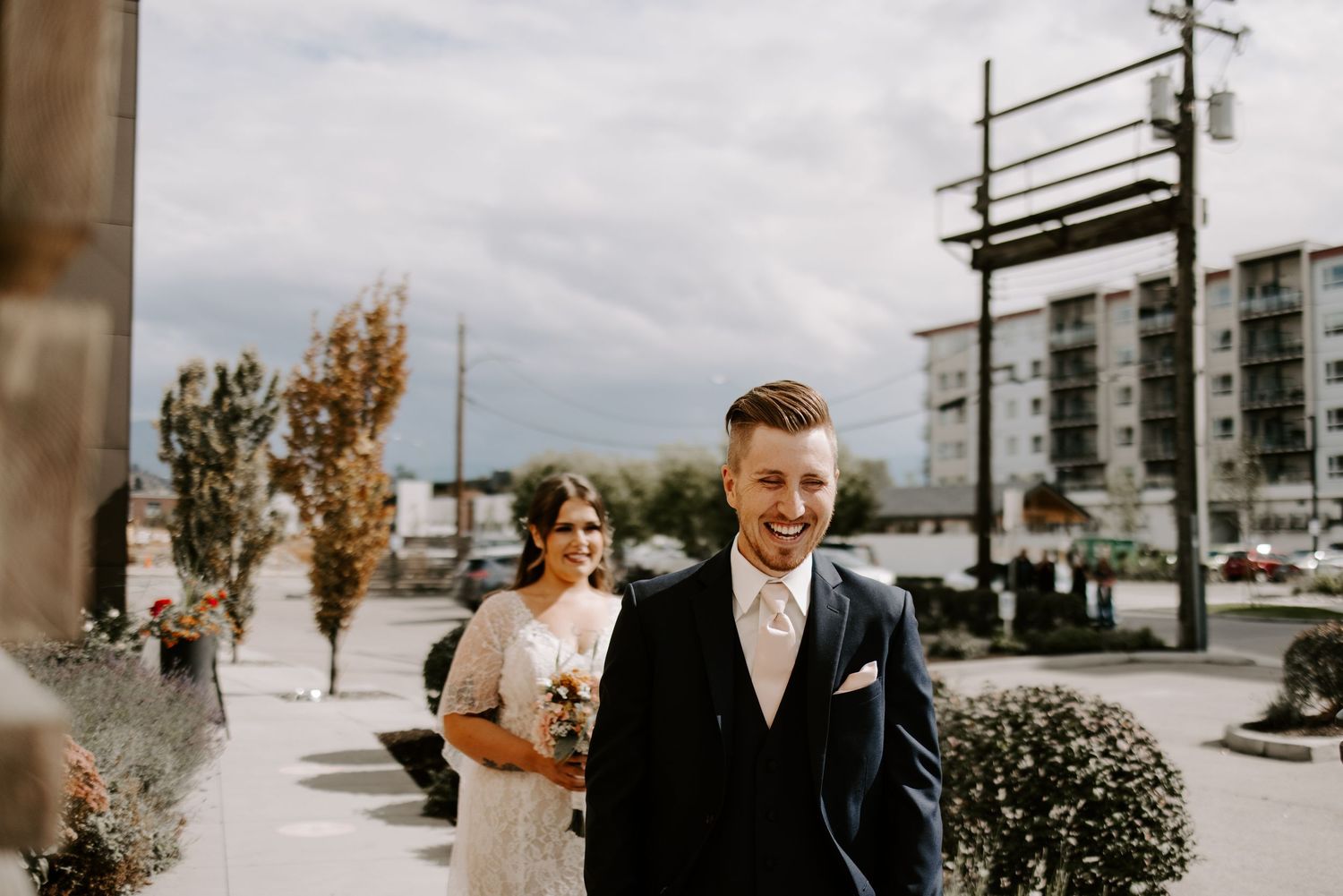 Outdoor wedding scene with urban architecture and autumn trees in the background.