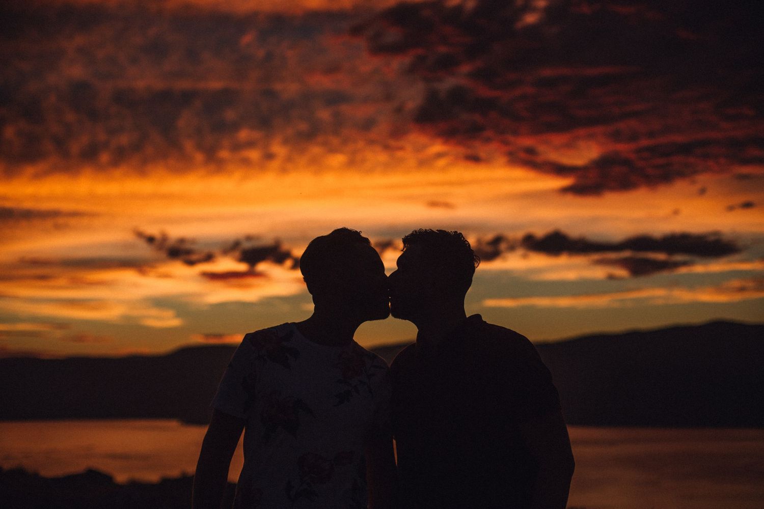 Dramatic silhouettes of a couple against a vibrant orange and purple sunset sky.