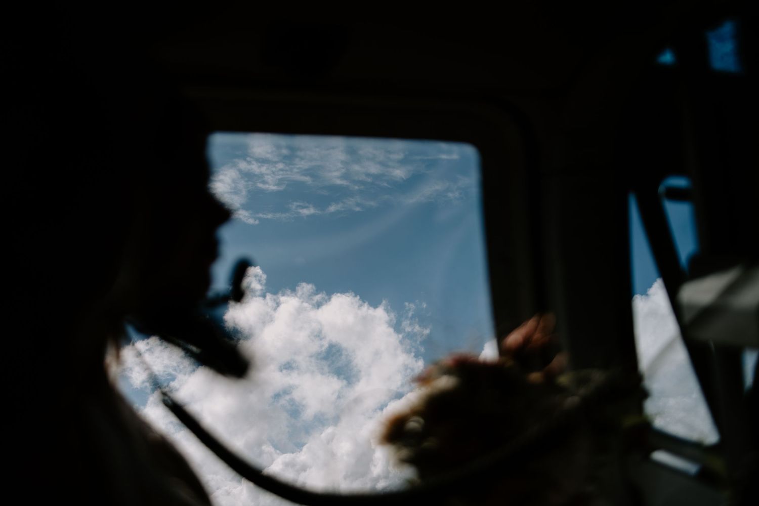 A series of seven photos showing white clouds against a blue sky through a car window.