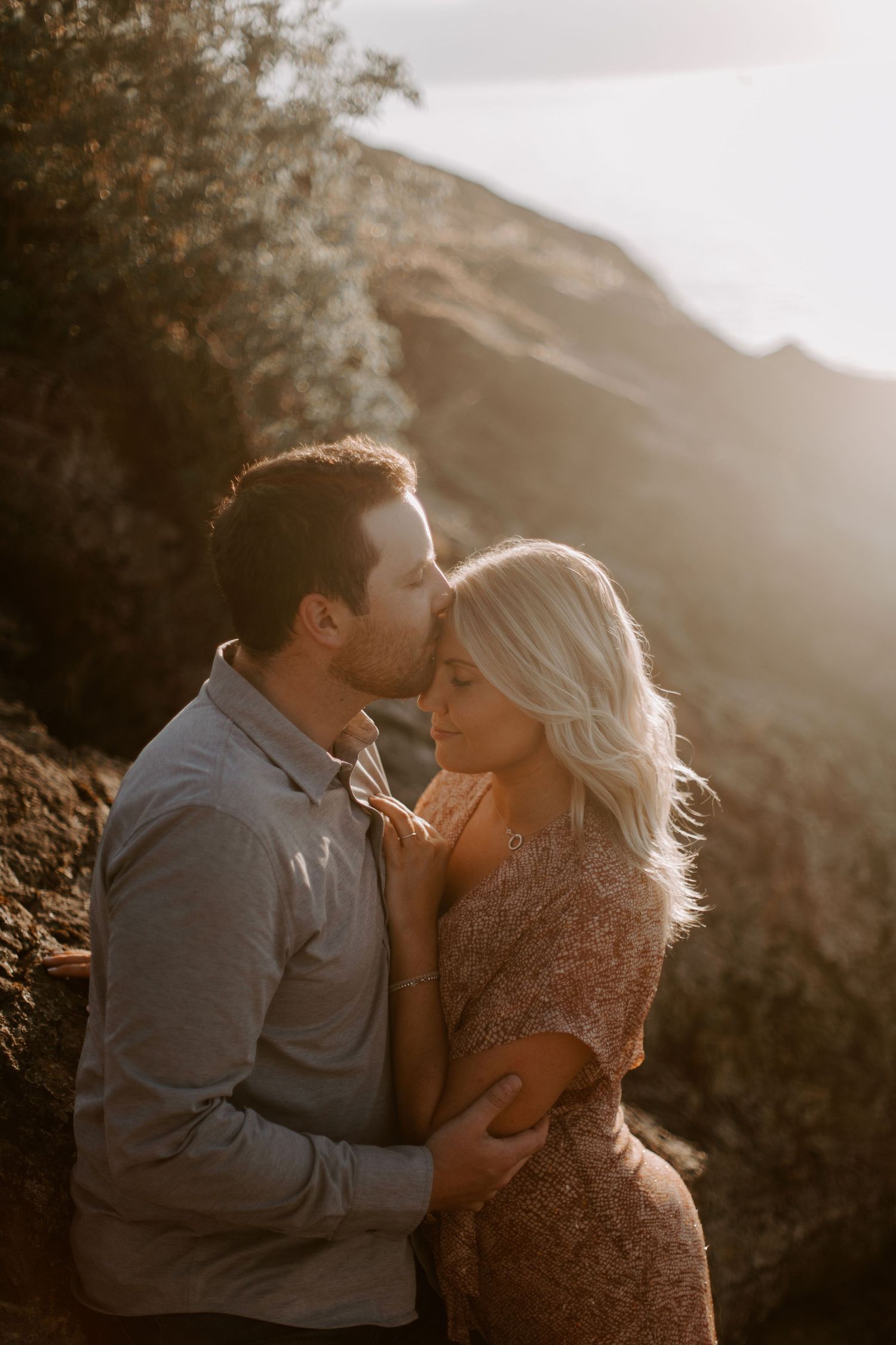 Intimate couple's photography session in golden sunlight with mountain scenery.