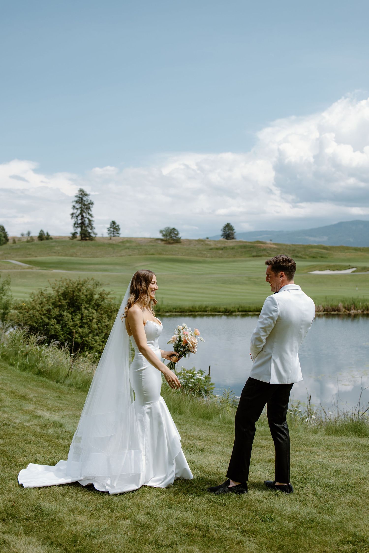 Scenic lakeside wedding photos with mountain views and green meadow.
