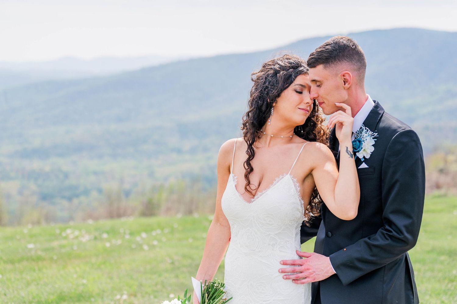 Couple shares intimate moment together outdoors with mountain landscape in background during spring wedding celebration.