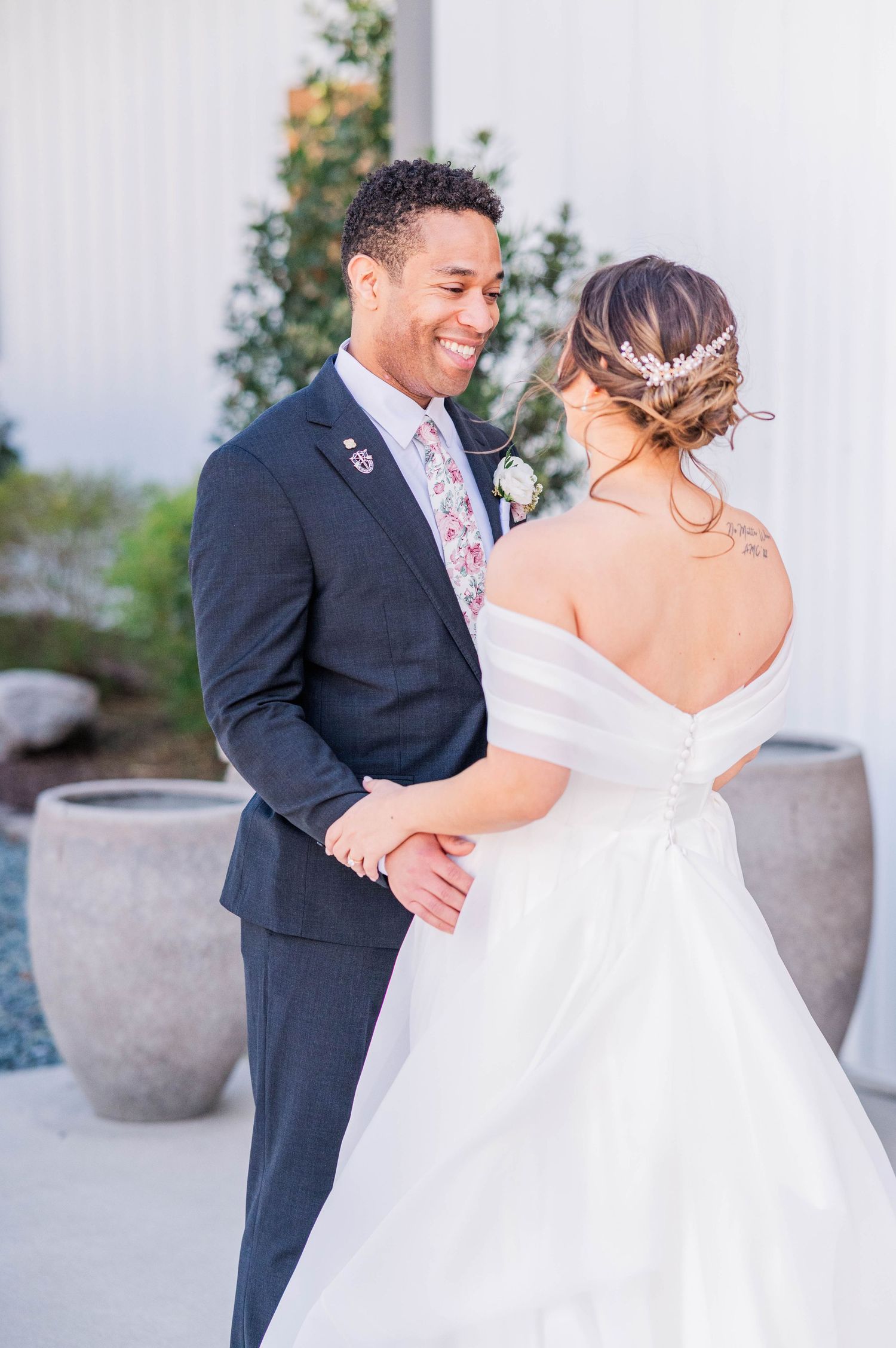 Bride and groom share a tender first look moment on their wedding day, with her wearing a white gown and him in a navy suit.