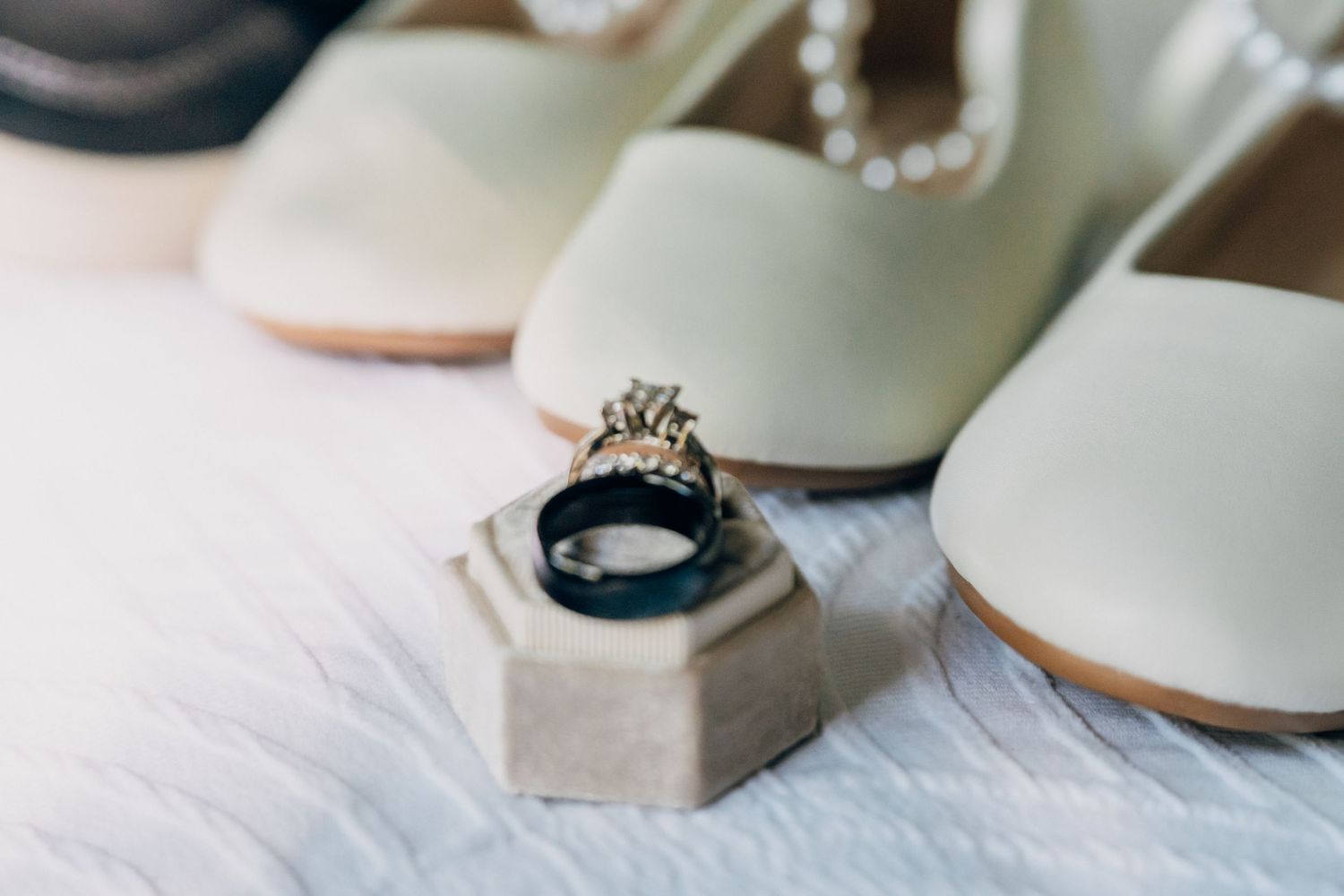 Wedding rings and jewelry details arranged on a soft white surface in natural light.