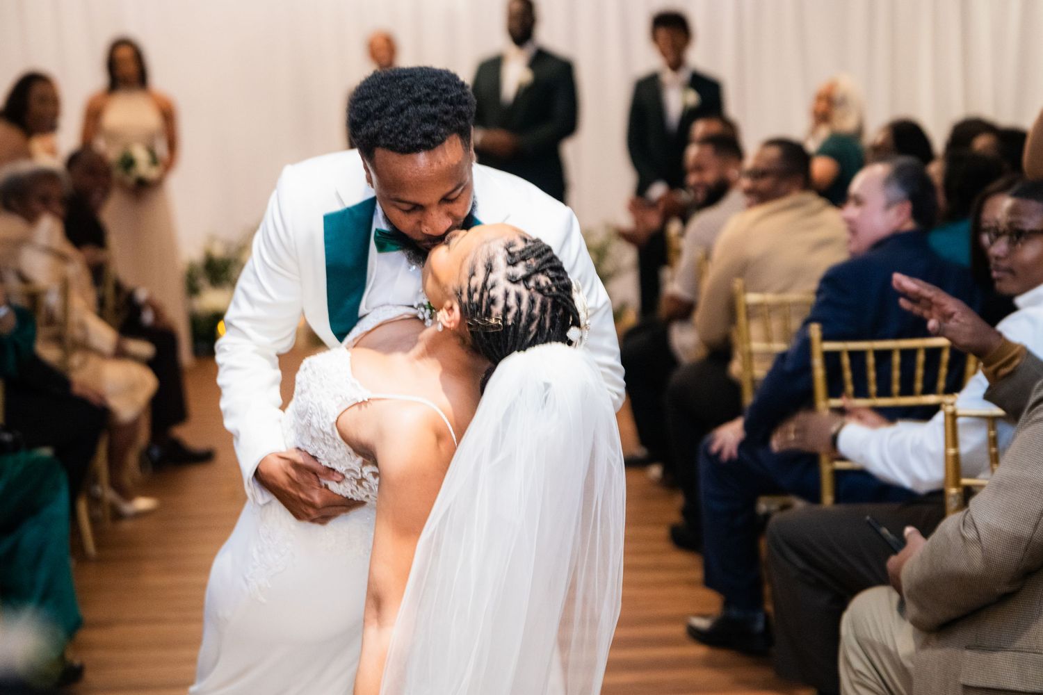 Newlyweds share a romantic dance at their wedding reception surrounded by seated guests.