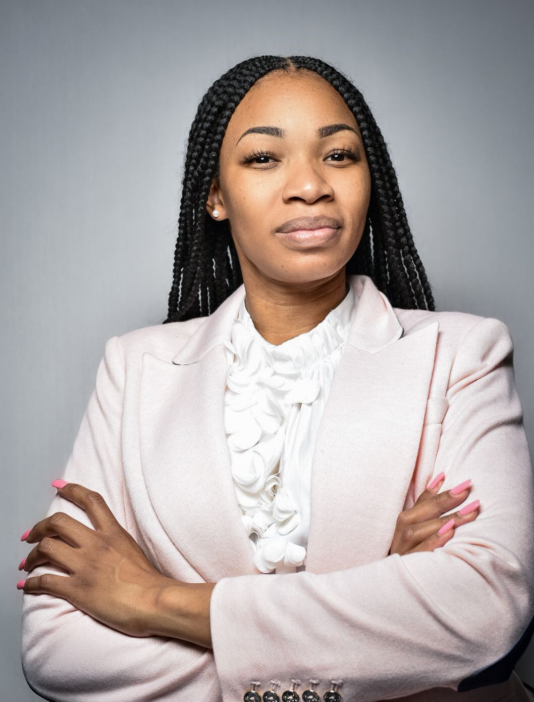 Professional headshot with person in light pink blazer and ruffled blouse.