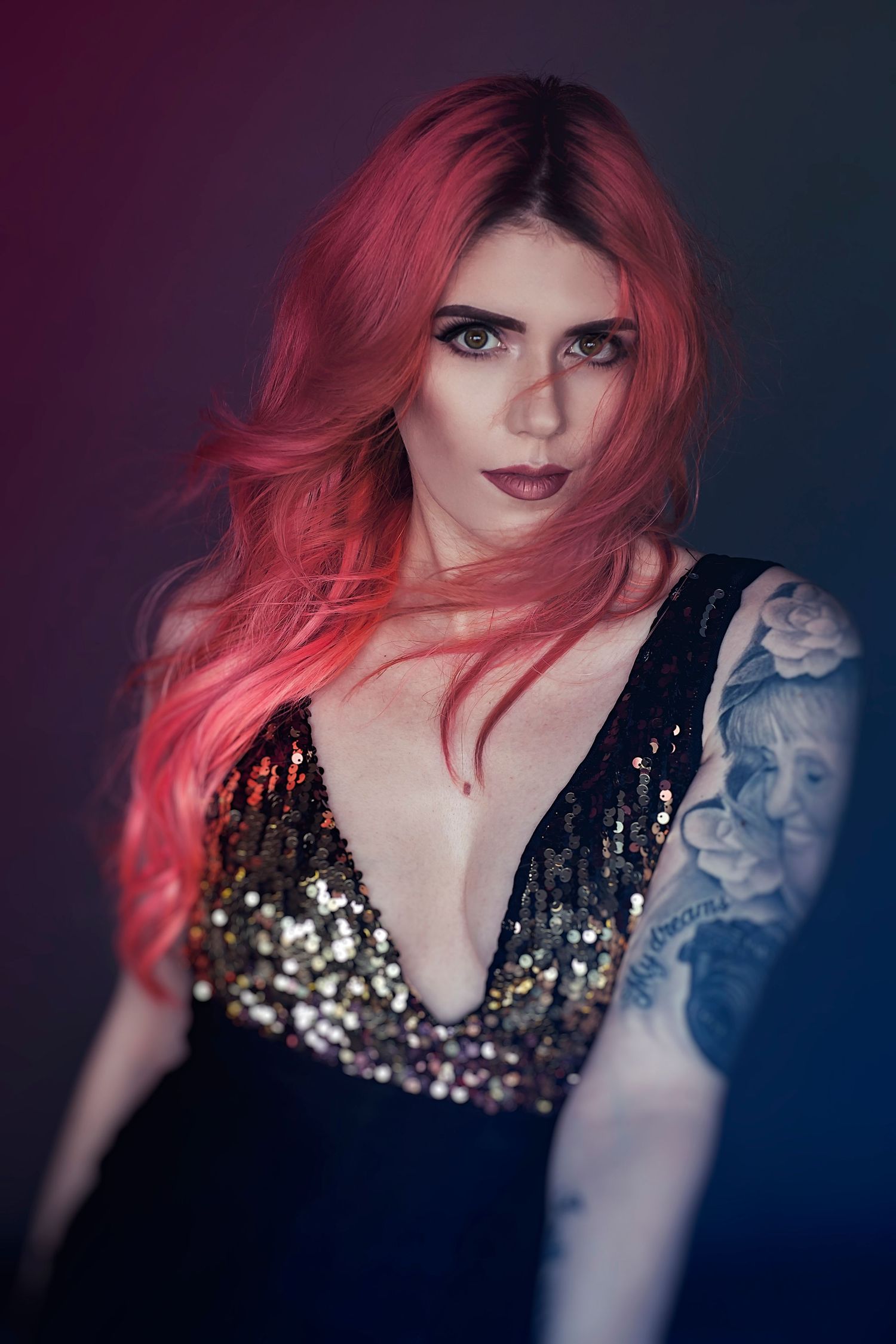 Dramatic portraits featuring bright red hair and sequined top against dark background.