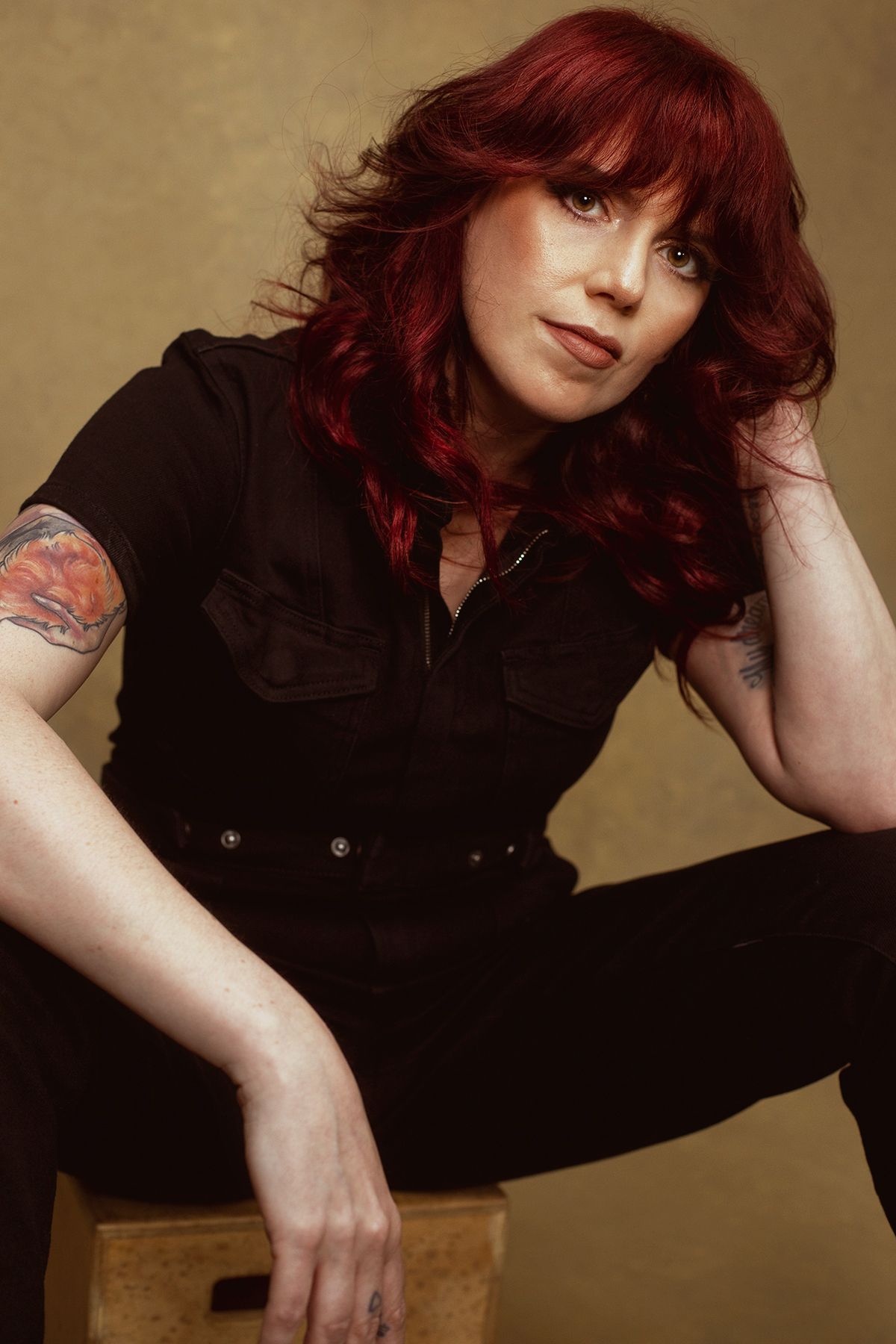Studio portraits in black outfit showing dynamic poses with wooden prop.