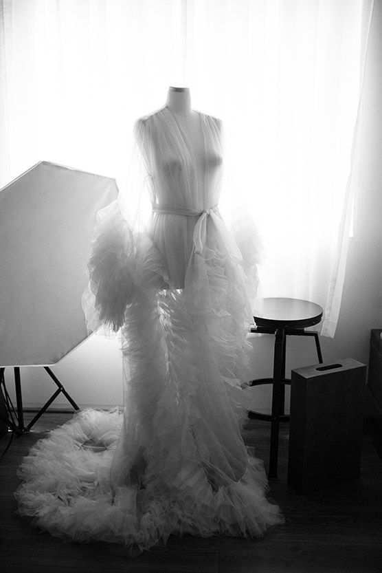 Silhouetted dress forms with flowing tulle fabric captured in backlit studio setting.