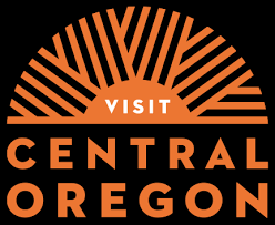 Visit Central Oregon logo featuring a orange sunburst design above bold text on a black background.