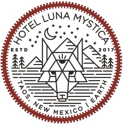 Circular logo for Hotel Luna Mystica, Taos New Mexico, featuring a geometric wolf head with mountains and pine trees.