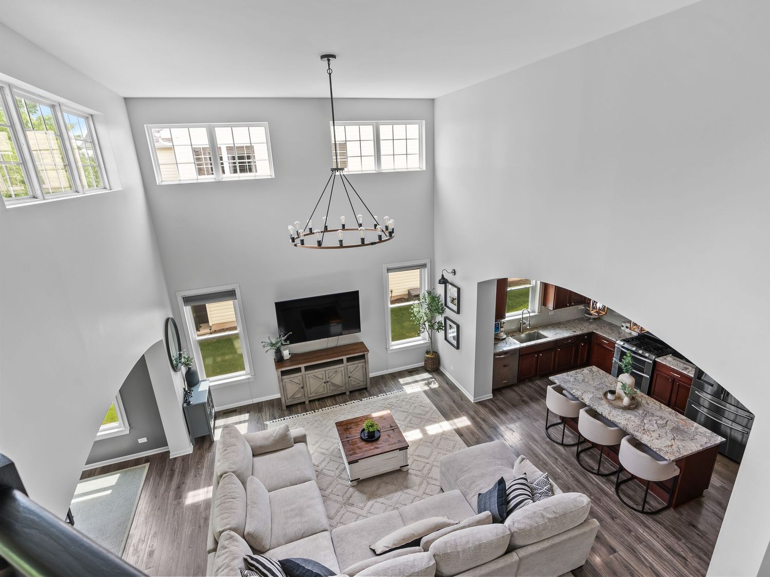High-angle view of a modern open-concept living room with vaulted ceiling, fireplace, and neutral gray decor.