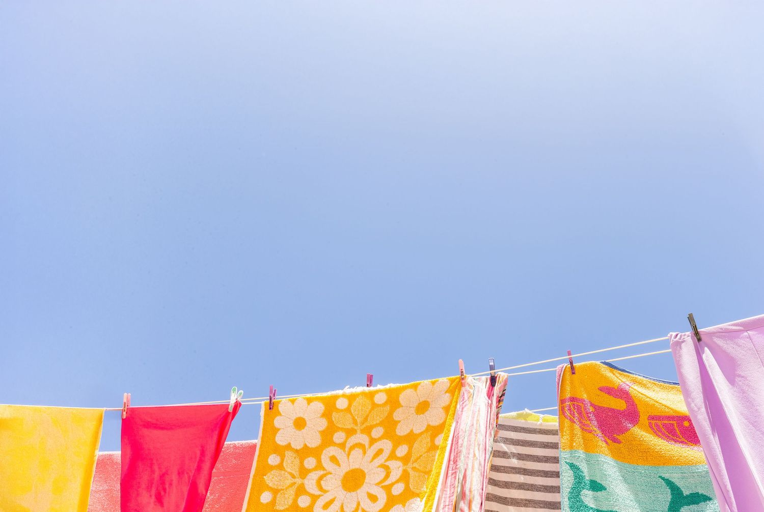 Colorful laundry hanging on clotheslines against a bright blue sky creates a vibrant outdoor display.