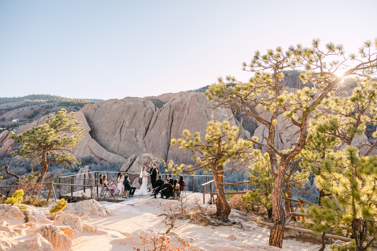 Panoramic view of scenic mountain overlook with autumn trees and visitors enjoying the natural landscape at sunset.