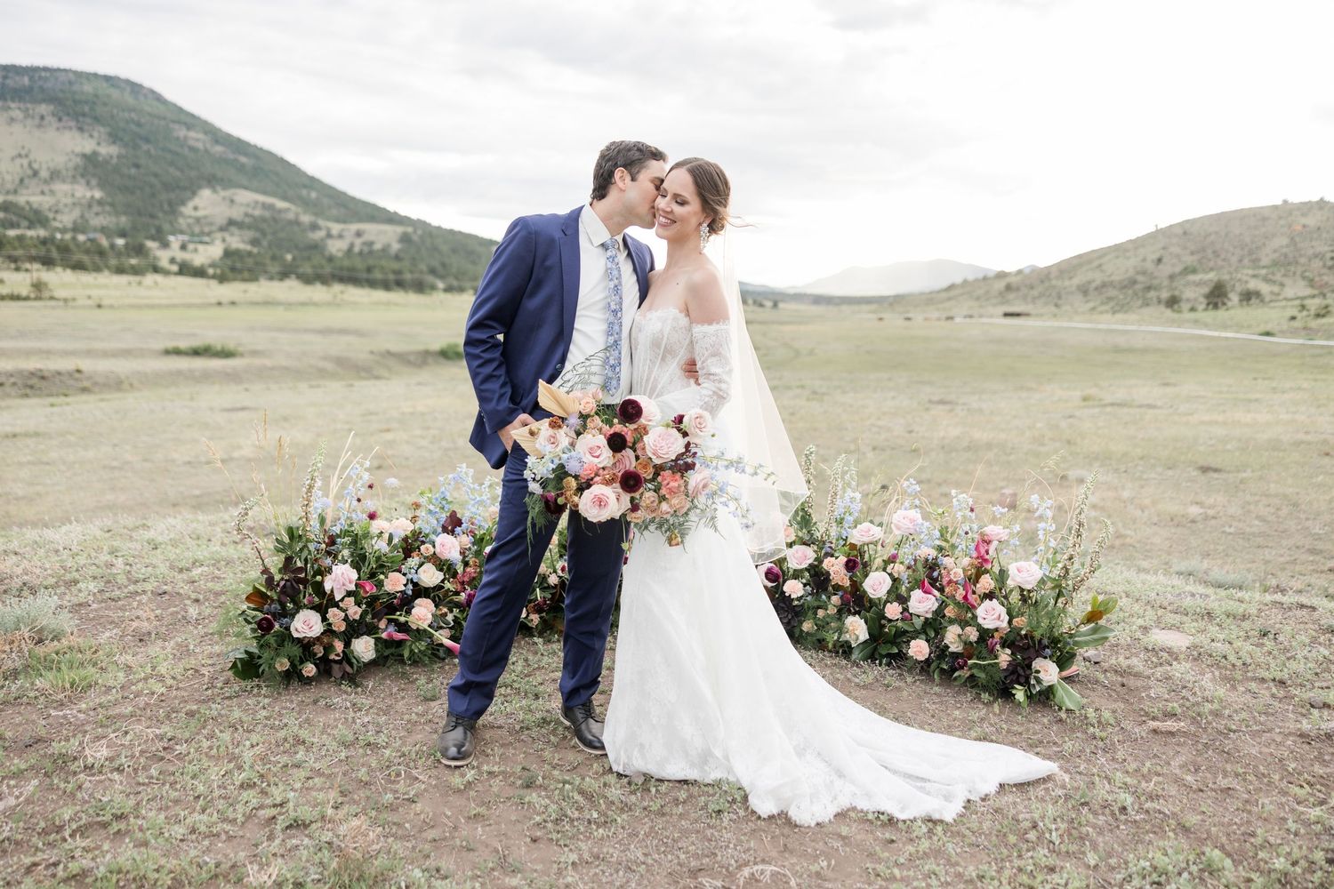 Colorado Wedding Photographer documents an outdoor mountain wedding ceremony setup with floral arrangements scenic hillside backdrop.
