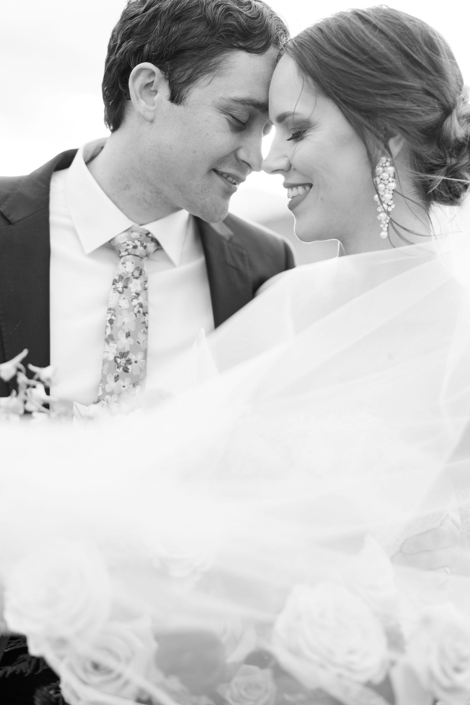 A romantic black and white wedding photo series showing tender moments between newlyweds with flowing white veil.